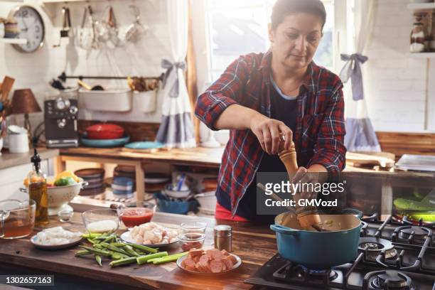 preparing cajun style chicken, shrimp and sausage jambalaya in a cast iron pot - chicken stew stock pictures, royalty-free photos & images