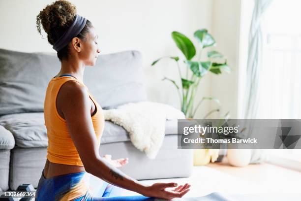 woman in lotus position while working out in living room of home - foco técnica de imágenes fotografías e imágenes de stock