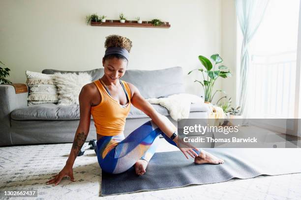 smiling woman stretching after working out in living room of home - yoga rug photos et images de collection