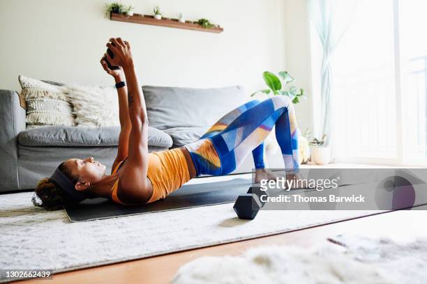 woman working out with weights while exercising in home - treina imagens e fotografias de stock