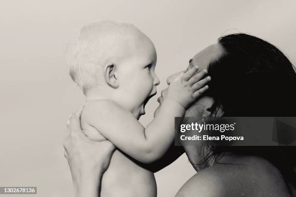 loving mother holding toddler boy, kissing and looking into his eyes - kissing hand stock-fotos und bilder