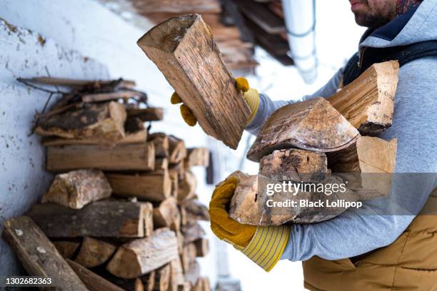 close up on a man who gathers firewood from the woodshed. - wooden shed stock pictures, royalty-free photos & images