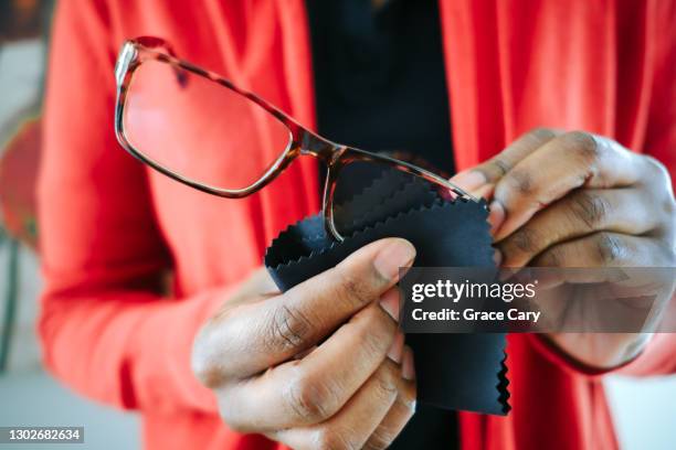 woman cleans eyeglasses with microfiber cloth - mikrofaser stock-fotos und bilder
