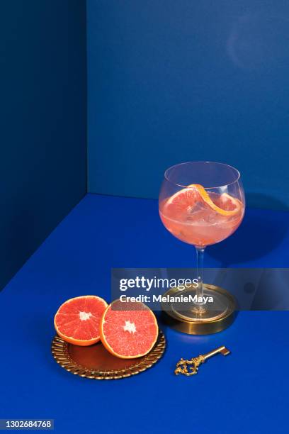 pop art stil gin cocktail mit grapefruit zitrusfrüchte in blauem hintergrund - 60s cocktail party stock-fotos und bilder