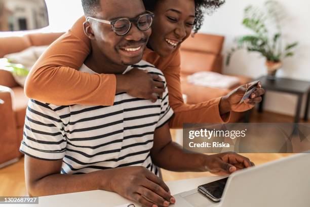 african american couple at home, using laptop and doing online shopping - shopping excitement stock pictures, royalty-free photos & images