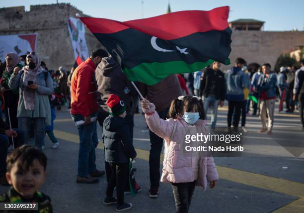 Girl waves a flag during a gathering to commemorate the tenth anniversary of the Arab Spring in Martyrs Square on February 17, 2021 in Tripoli,...
