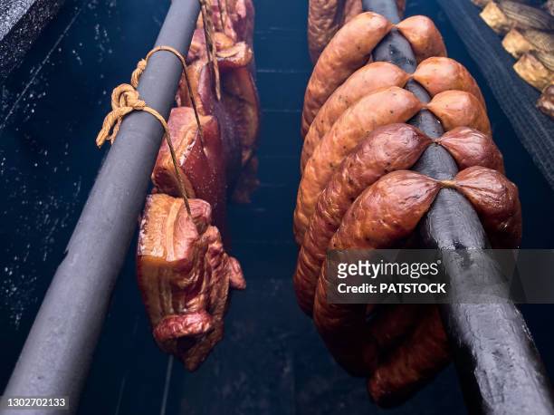 bacon and sausages hanging on rack in a smokehouse. - smoking meat stock pictures, royalty-free photos & images