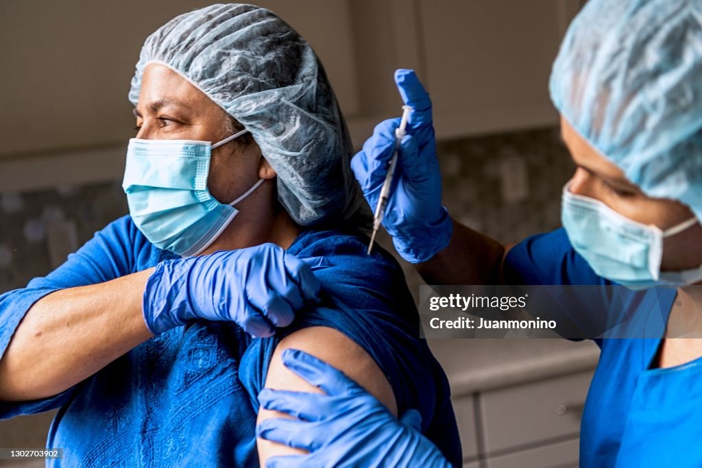 Female nurse being vaccinated by a coworker