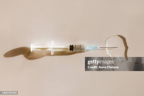 syringe in puddle of vaccine - botox fotografías e imágenes de stock