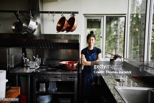 portrait of smiling female chef standing in commercial kitchen - chef leader - fotografias e filmes do acervo