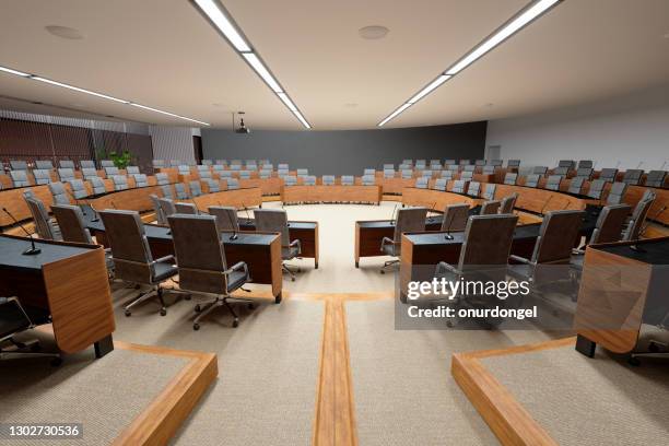 interior of an empty conference hall with gray color seats, microphones on the desks and carpeted flooring. - federal convention stock pictures, royalty-free photos & images