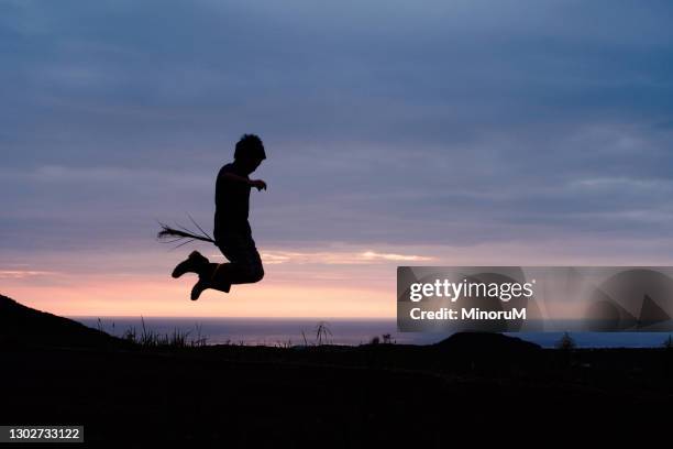 boy's silhouette jumping in the morning glow - witch flying on broom stock-fotos und bilder