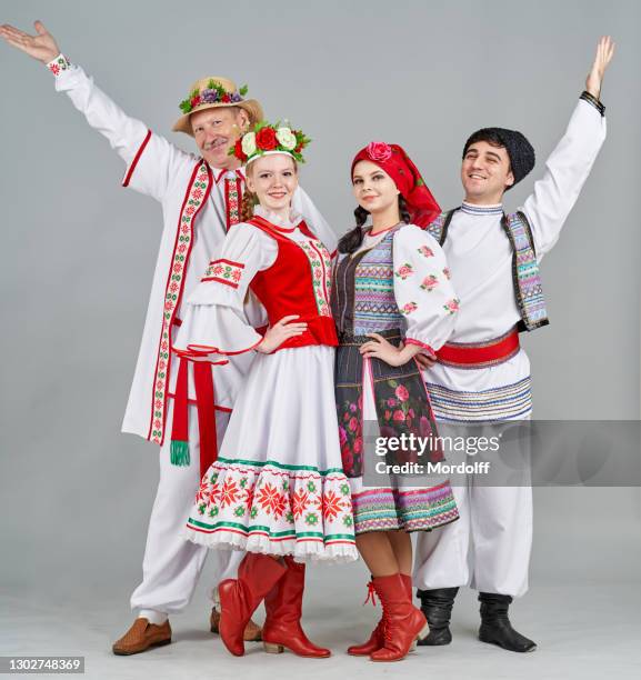 due coppie di ballerini in bielorussia e moldavia vestiti popolari sono in piedi e guardano allegramente la macchina fotografica - abito da cerimonia foto e immagini stock