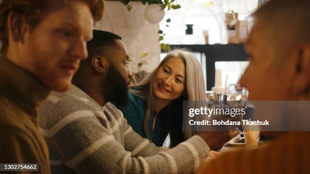 group of friends with glasses talk sitting at bar countertop - cosy pub stock pictures, royalty-free photos & images