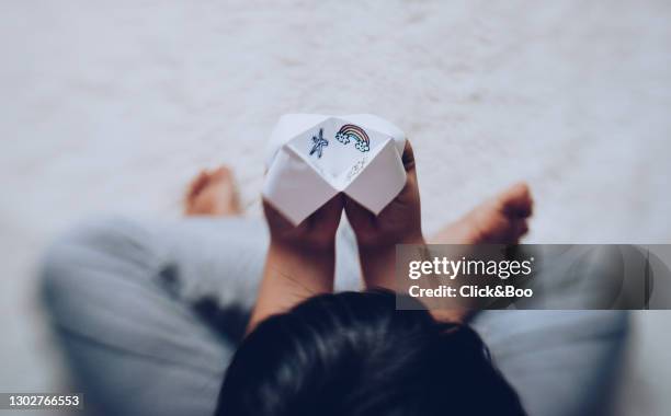 a boy playing with a origami fortune teller - origami spiel stock-fotos und bilder