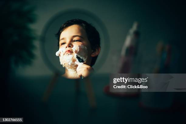 little boy pretending shaving on mirror - rasieren stock-fotos und bilder