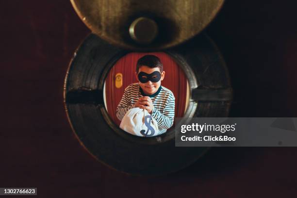 kid viewed through a peephole pretending be a thief. - peephole stock-fotos und bilder