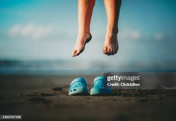 kid feet on the beach jumping on his blue clogs - le soulier qui vole photos et images de collection