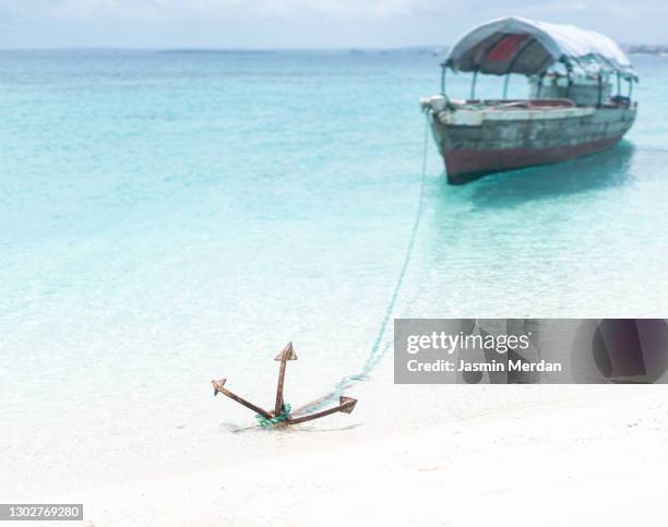 boat anchored near beach in turquoise sea - être ancré photos et images de collection