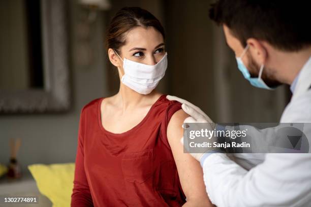 young woman rolled a sleeve. - flu vaccine stock pictures, royalty-free photos & images