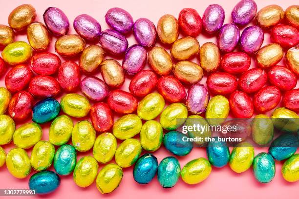directly above shot of colourful chocolate easter eggs on pink background - chocolate easter egg stock pictures, royalty-free photos & images