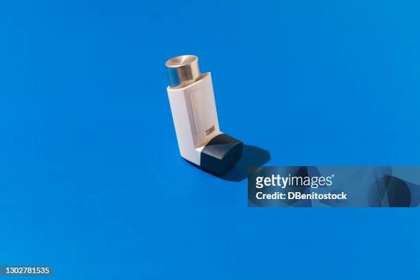asthma inhaler on blue background. medicine and breathing disorder concept - asthma stockfoto's en -beelden