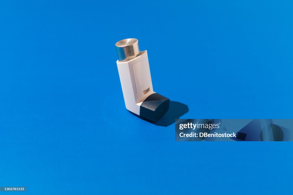 Asthma inhaler on blue background. Medicine and breathing disorder concept