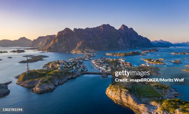 aerial view, evening sun over henningsvaer with football stadium, rock islands in the sea off bergen, festvagtinden, vestvagoey, lofoten, nordland, norway - henningsvaer stock pictures, royalty-free photos & images