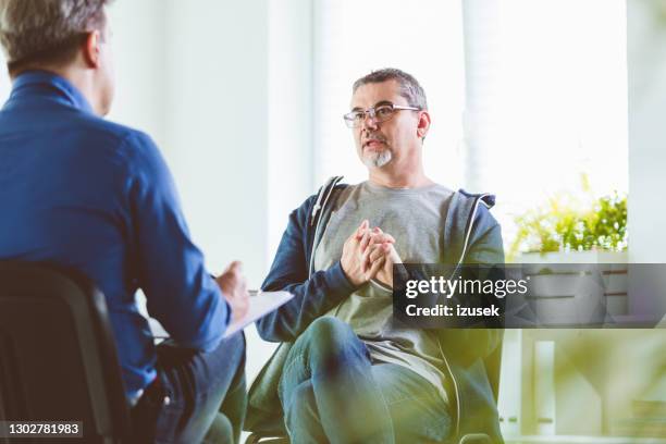 mature man talking with psychotherapist in his office - cancer support stock pictures, royalty-free photos & images