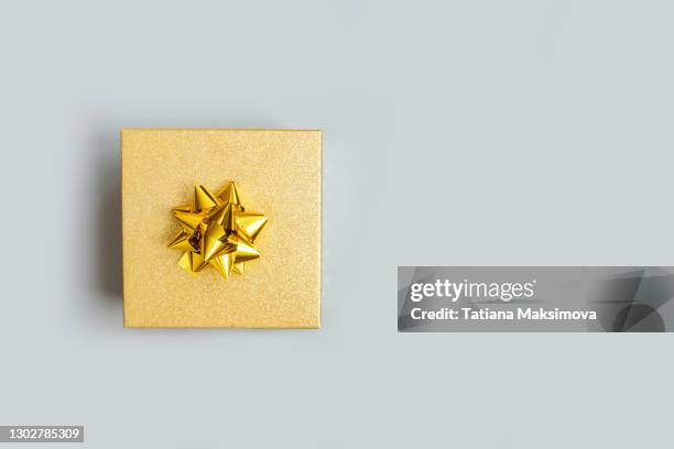 gift box with golden bow on gray. copy space. - gift box tag stock-fotos und bilder