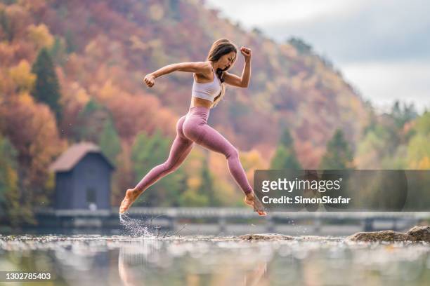 young woman jumping over water in the nature - slim stock pictures, royalty-free photos & images