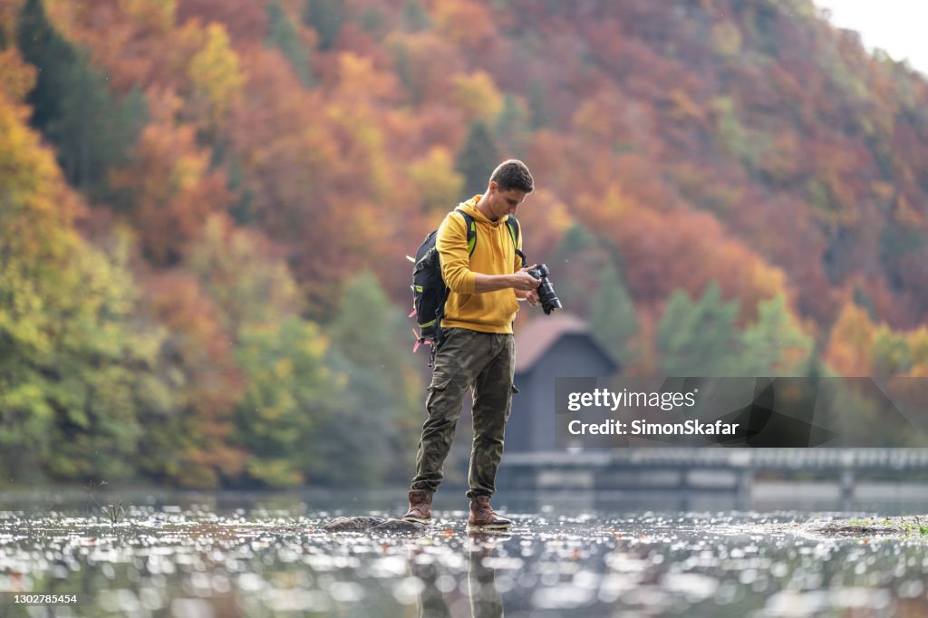 Male photographer holding camera in lake
