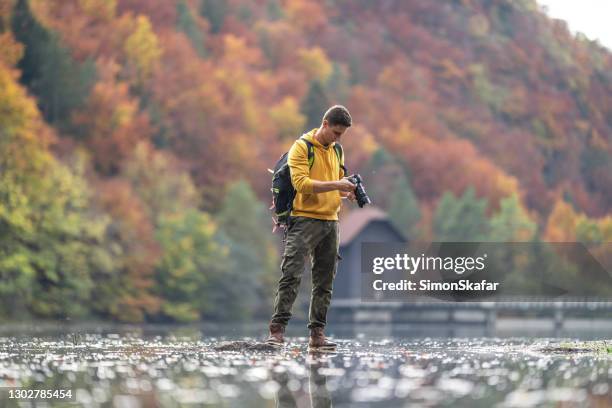 male photographer holding camera in lake - digital single lens reflex camera stock pictures, royalty-free photos & images