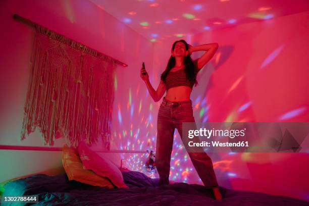 cheerful woman dancing while partying in bedroom - room after party stock pictures, royalty-free photos & images