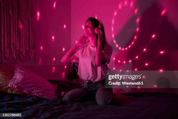 young woman enjoying music in bedroom at home - lila stockfoto's en -beelden