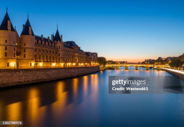 france, ile-de-france, paris, conciergerie and seine canal at dusk with pont neuf in background - conciergerie foto e immagini stock