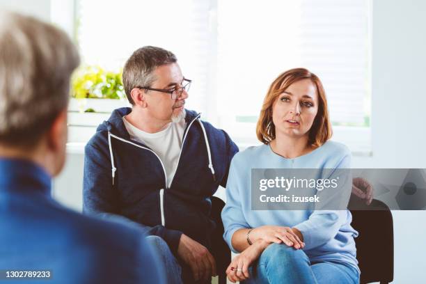 troubled couple talking with psychotherapist - couple counselling stock pictures, royalty-free photos & images