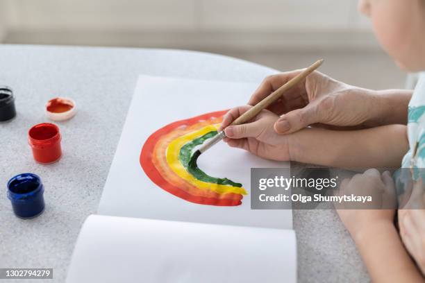 hands of a child in the hands of an adult learn to draw a rainbow - baby paint hand imagens e fotografias de stock