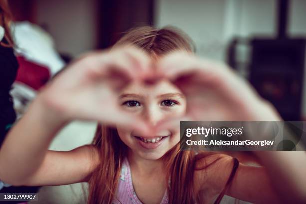 smiling female child making heart shape with hands - child love heart hands stock pictures, royalty-free photos & images