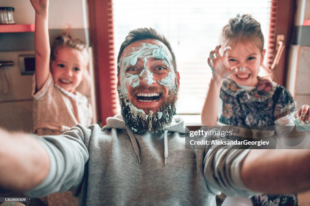 Selfie del padre con figlie carine dopo aver cucinato e fatto casino con il condimento