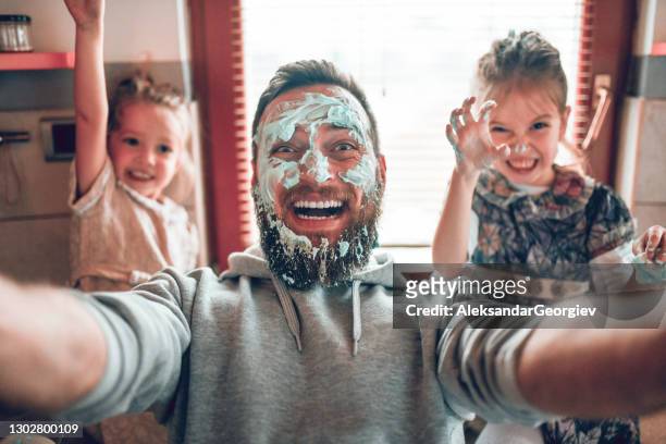 selfie by father with cute child daughters after cooking and making mess with topping - father stock pictures, royalty-free photos & images