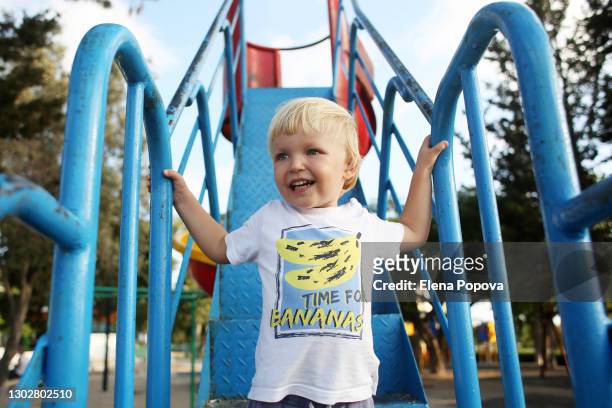 cute blond boy 2-3 y.o. playing at the playground at summer sunny day - eurasia fotografías e imágenes de stock