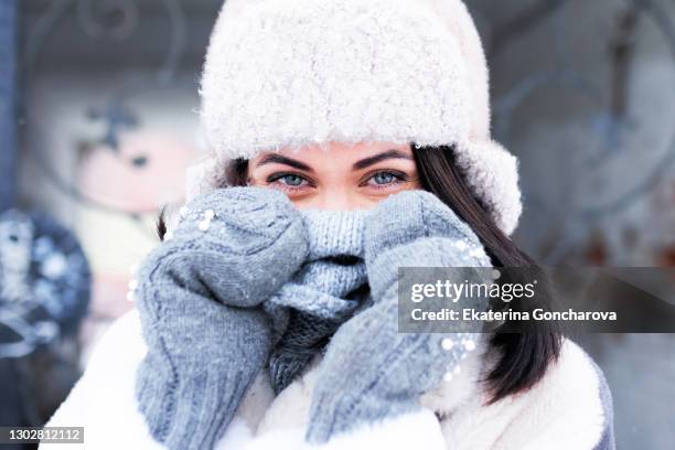 close-up of a beautiful female face in a hat and mittens . looking at the camera - warme kleding stockfoto's en -beelden