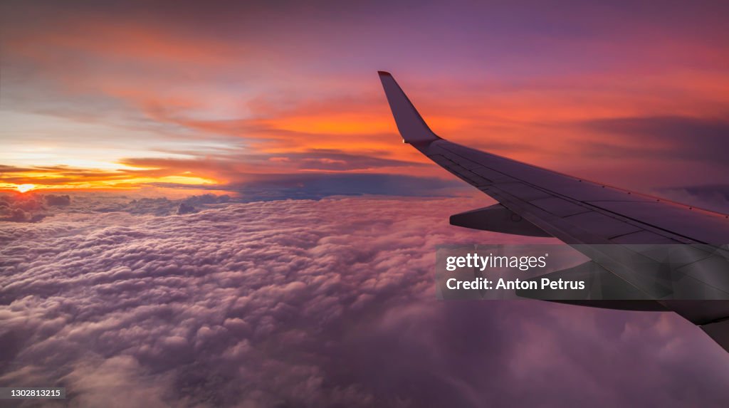 View from the airplane window on a beautiful sunset above the clouds.