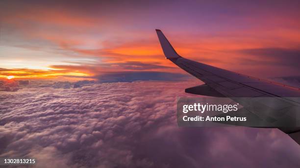 view from the airplane window on a beautiful sunset above the clouds. - airplane window stockfoto's en -beelden