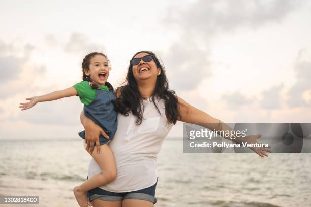 mother and daughter arms outstretched on the beach - open day 2 stock pictures, royalty-free photos & images