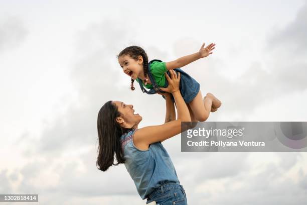 bambina che gioca in aereo tra le braccia di sua madre - sollevare foto e immagini stock