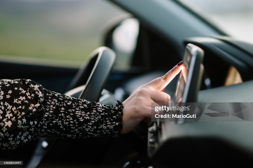 Vrouw die het aanrakingsscherm van een auto raakt
