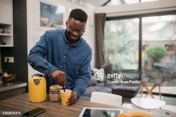 jeune homme afro-américain heureux préparant le thé à la maison - bouilloire photos et images de collection