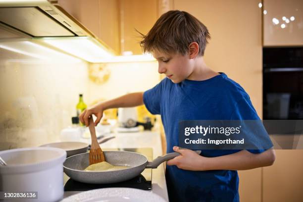 kleiner junge hilft, crepes pfannkuchen in der küche - pancake toss stock-fotos und bilder
